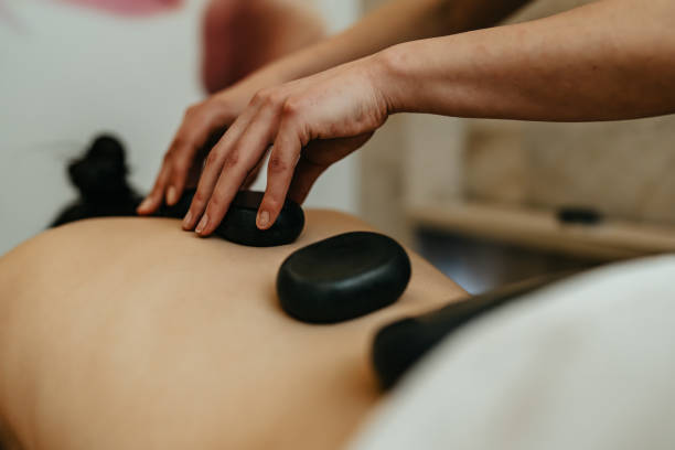 Professional therapist providing hot stone massage at home in Dubai using heated stones for deep relaxation and stress relief.